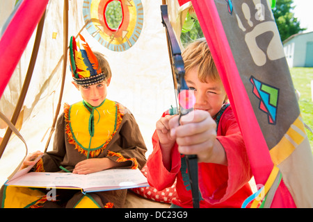 Frères vêtus de costumes autochtones américaines jouant en tipi, portrait Banque D'Images