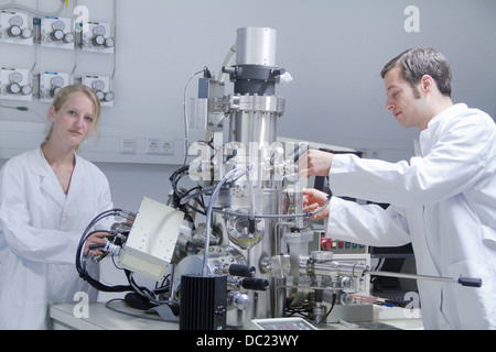 Deux scientifiques de porter des blouses de laboratoire à l'aide de matériel scientifique Banque D'Images