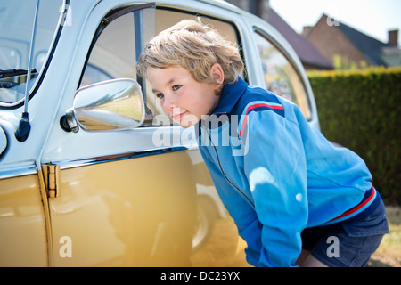 Garçon à la recherche de l'aile de voiture miroir Banque D'Images