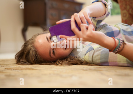 Teenage girl lying on floor with cell phone Banque D'Images