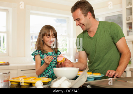 Jeune fille avec grand frère cupcakes glaçage Banque D'Images