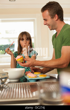 Jeune fille avec grand frère cupcakes glaçage Banque D'Images