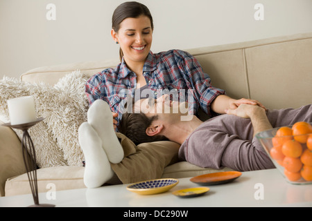 Couple on sofa, l'homme avec la tête sur les genoux de femme Banque D'Images