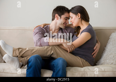 Couple on sofa, femme assise sur les genoux de l'homme Banque D'Images