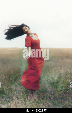 Une femme dans une robe rouge danse sur un champ Banque D'Images