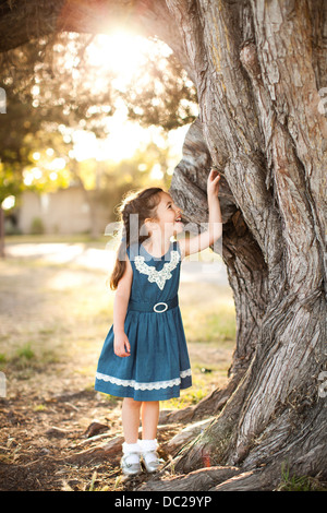 Portrait of Girl touching tronc de l'arbre Banque D'Images