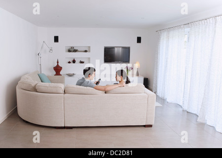 Mari et femme se détendre sur canapé d'angle dans la salle de séjour Banque D'Images
