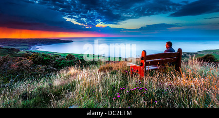 Ron place à Ravenscar North York Moors pendant que quelqu'un observe le soleil sur Robin Hoods Bay Banque D'Images