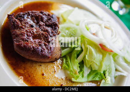 Servant de steak avec une variété de légumes colorés et garnis et habillés de goût appétissant sur une plaque Banque D'Images
