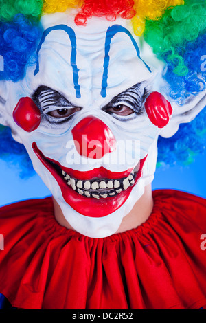 Clown effrayant masque clown en personne sur fond bleu studio shot Banque D'Images