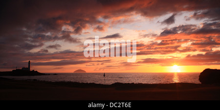 Coucher de soleil sur l'Ailsa Craig avec phare, orange Ciel et nuages et du pavillon de golf. Banque D'Images