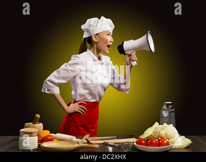 Asian female chef criant dans un mégaphone Banque D'Images