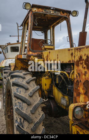 Un tracteur jaune rouillé, qui a connu des jours meilleurs quand il a été utilisé pour le remorquage de bateaux sur le rivage dans l'estuaire de la Humber. Banque D'Images