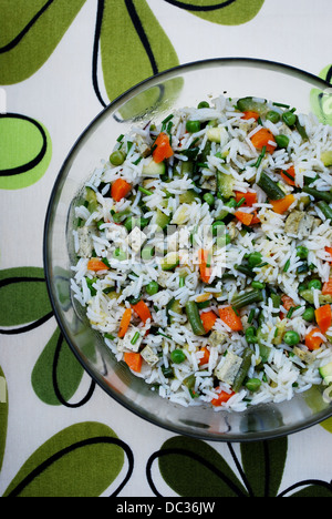 Salade végétarienne du riz blanc avec un mélange de légumes et le tofu dans un bol en verre sur fond coloré Banque D'Images