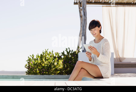 Smiling woman using digital tablet at poolside Banque D'Images