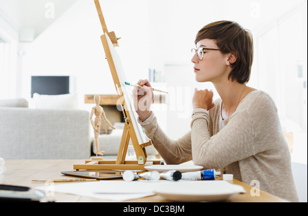 Woman painting on easel at table Banque D'Images