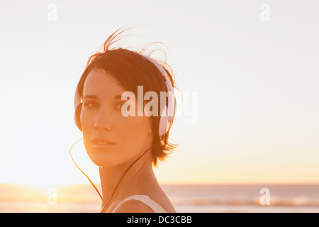 Close up portrait of smiling woman wearing headphones at beach Banque D'Images