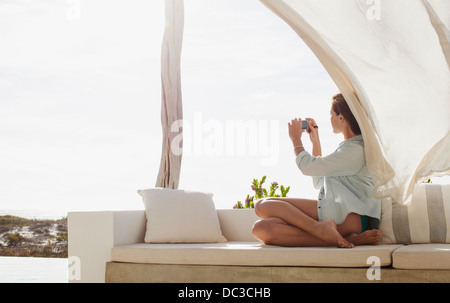 Woman taking photograph on sunny patio Banque D'Images