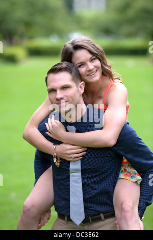 Un jeune couple dans un jardin avec l'homme avec son fiancé sur son dos. Banque D'Images