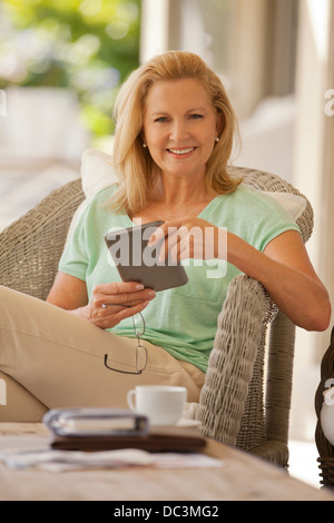Portrait of smiling woman using digital tablet on porch Banque D'Images