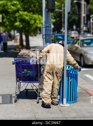 Sans-abri avec un panier les charognards dans une poubelle, Seattle, Washington, USA Banque D'Images