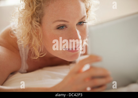 Close up of woman using digital tablet in bed Banque D'Images