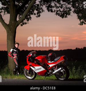 Motocycliste regardant sa Ducati dans la lumière du soir Banque D'Images