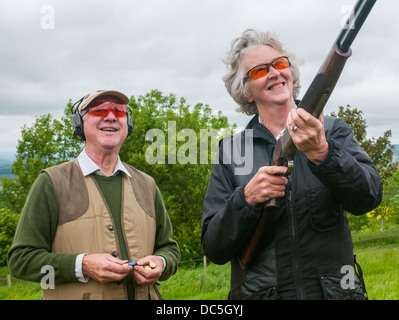 Un fusil de tir dame à un jeu de simulation de tir d'argile 24, aidé par un chargeur Banque D'Images