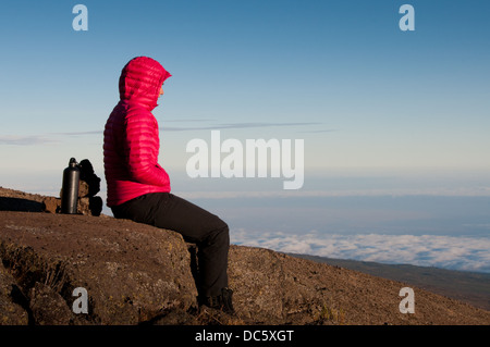 Femme assise sur des rochers surplombant la savane africaine Banque D'Images