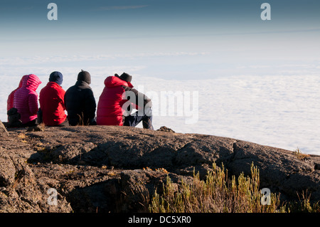 Une équipe de trekkeurs gazing plus tôt le matin nuages sur le sommet du Kilimandjaro trek Banque D'Images