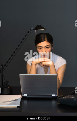Businesswoman working on laptop at night Banque D'Images