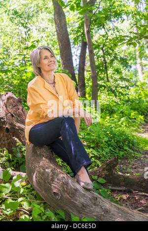 USA, New York State, New York, Central Park, Senior woman sitting on log in forest Banque D'Images