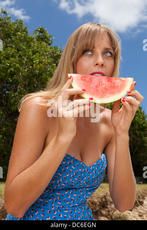 Une blonde woman mange de la pastèque à hawaii. Banque D'Images