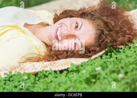 Portrait of young woman lying on grass in park Banque D'Images