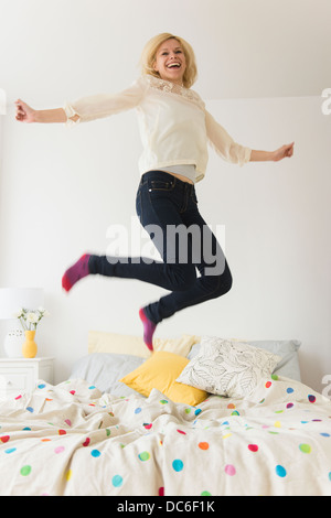 Young woman jumping on bed Banque D'Images