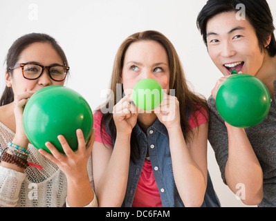 Portrait de jeunes femmes et man blowing green balloons Banque D'Images