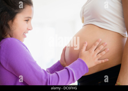 Girl (8-9) touching pregnant mother's belly Banque D'Images