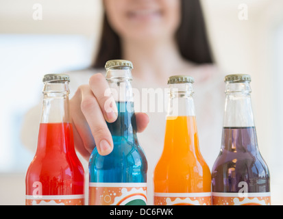 Young woman reaching colorées pour bouteilles de soda Banque D'Images