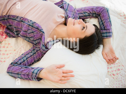 Portrait de jeune femme détendue lying down on bed Banque D'Images