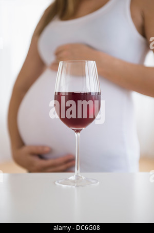 Mid section of pregnant woman, vin rouge à l'avant Banque D'Images