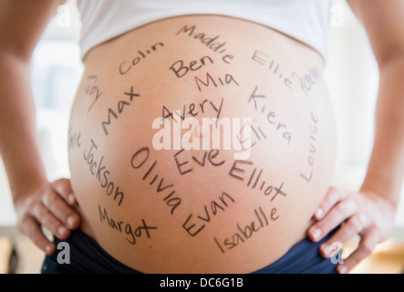 Mid section of pregnant woman avec noms écrits sur son ventre Banque D'Images