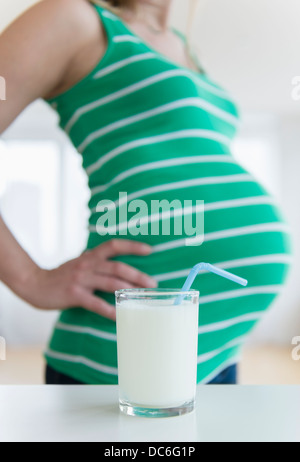 Mid section of pregnant woman, verre de lait à l'avant Banque D'Images