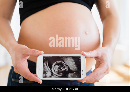 Mid section of pregnant woman holding mobile phone Banque D'Images