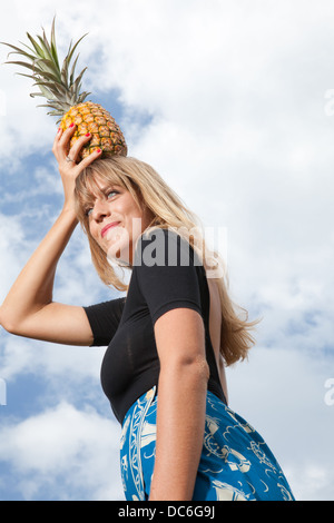 Une blonde woman holding est un ananas sur sa tête. Banque D'Images