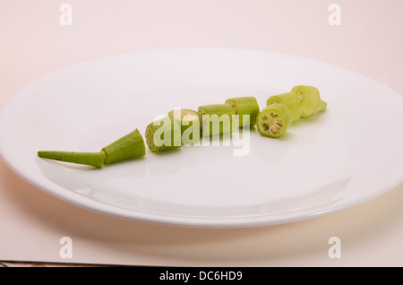 Dés de okra pod sur une soucoupe blanche. Banque D'Images