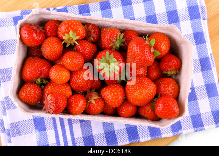 Des fraises fraîches dans du papier fort sur fond bleu-blanc, vue du dessus Banque D'Images