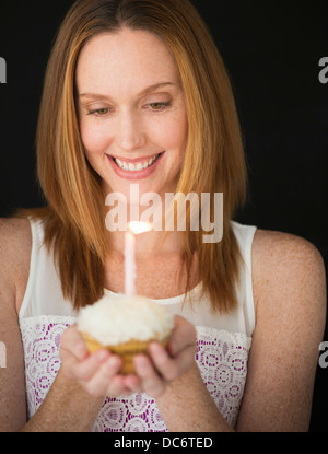 Woman holding birthday cupcake Banque D'Images