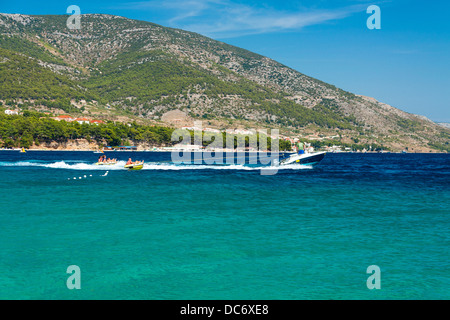 Les touristes dans des tubes d'être tiré par un bateau à moteur à Bol sur l'île de Brač, Croatie Banque D'Images