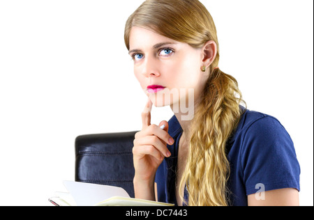 Jolie jeune femme penser lors de l'écriture sur le bloc-notes Banque D'Images