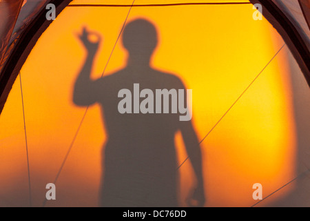 Silhouette of man gesturing ok reflétée sur une tente Banque D'Images